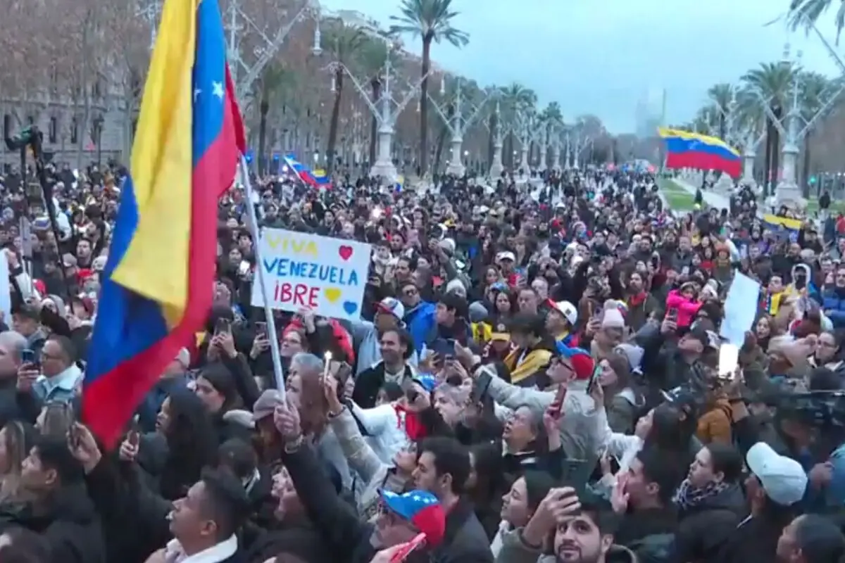 Multitudinaria manifestación con banderas de Venezuela y un cartel que dice Viva Venezuela libre en una avenida arbolada Multitudinaria manifestación con banderas de Venezuela y un cartel que dice Viva Venezuela libre en una avenida arbolada