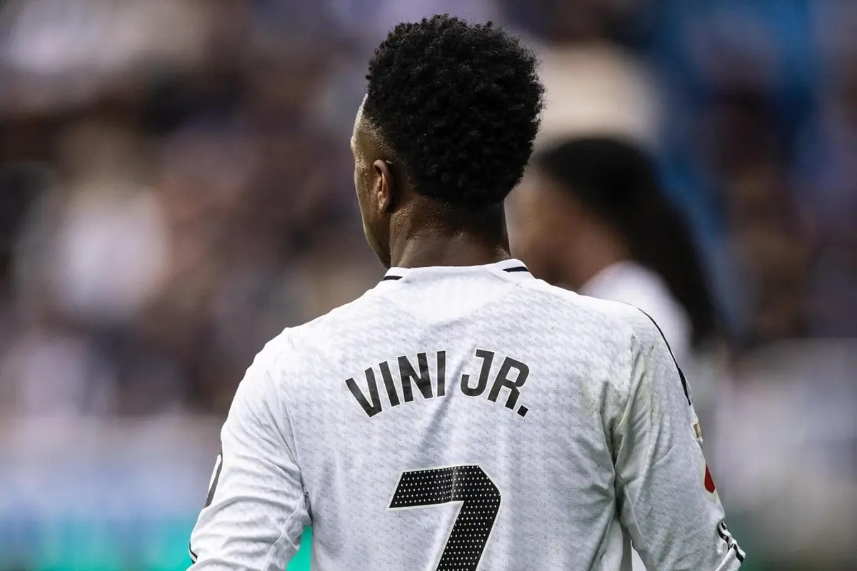 Futbolista d’esquena amb samarreta blanca amb el número 7 i el nom Vini Jr en un estadi desenfocat