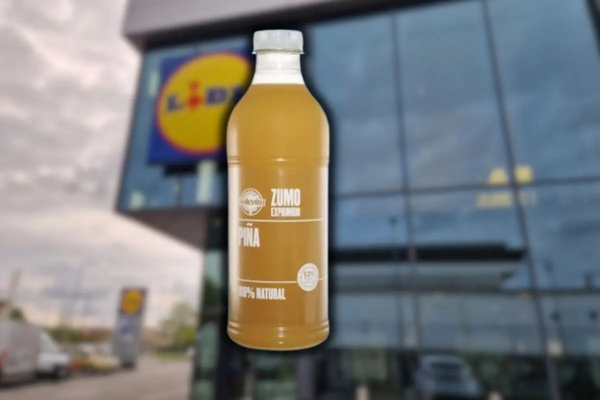 Botella de zumo de piña 100% natural de la marca Solevita en primer plano con la fachada de un supermercado Lidl desenfocada al fondo