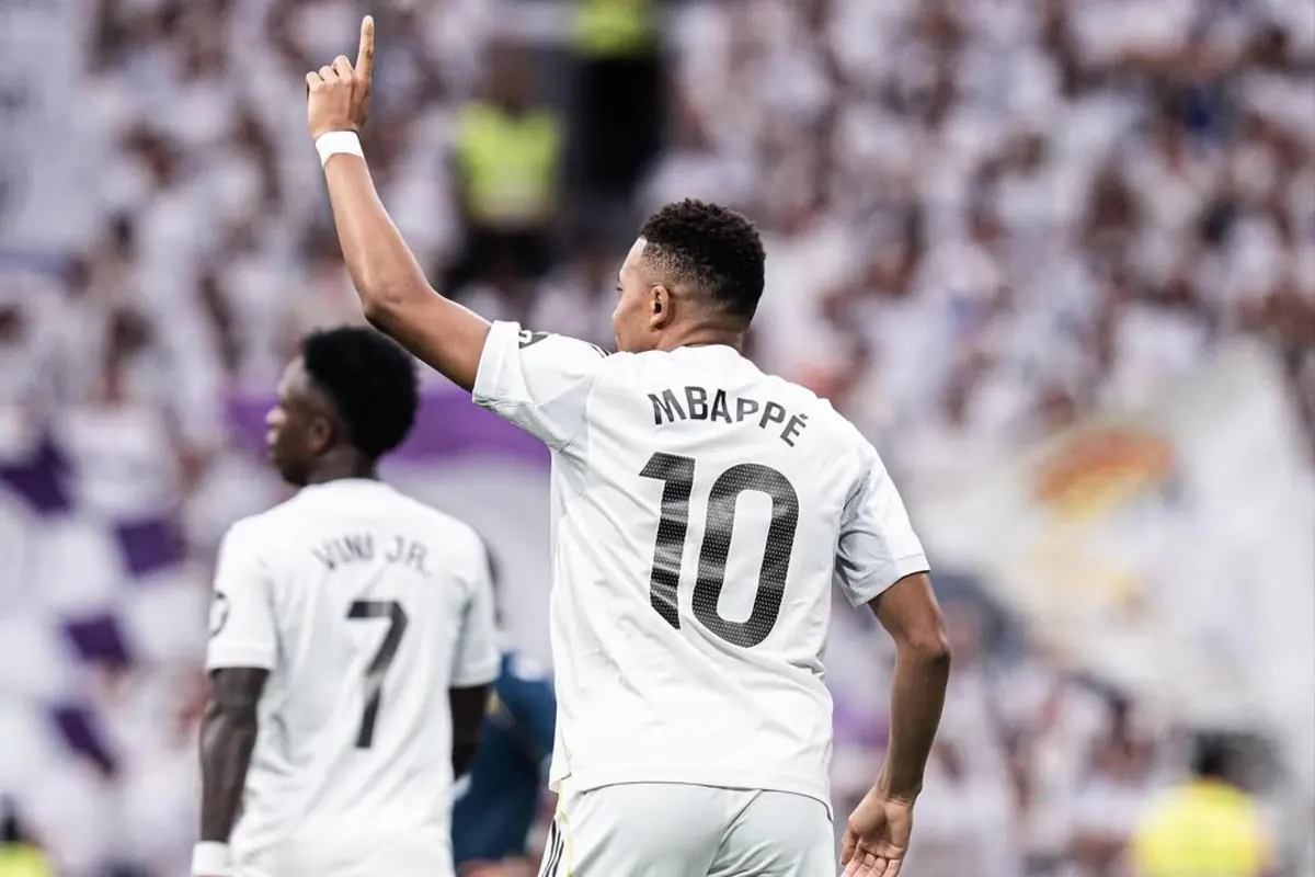 Futbolista amb samarreta blanca número 10 aixecant un braç en un estadi ple durant un partit