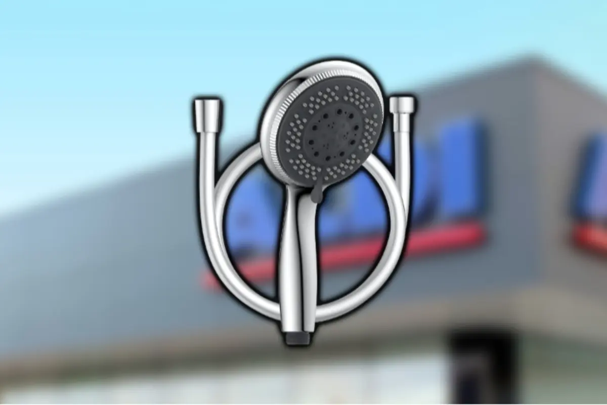 Cabezal de ducha de mano plateado con manguera flexible y múltiples chorros sobre un fondo borroso de edificio comercial