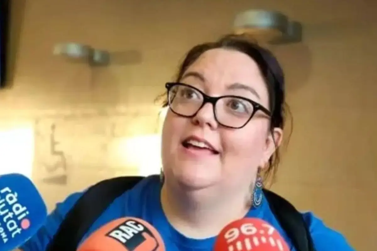 Dona amb ulleres i samarreta blava parlant somrient davant de diversos micròfons de ràdio