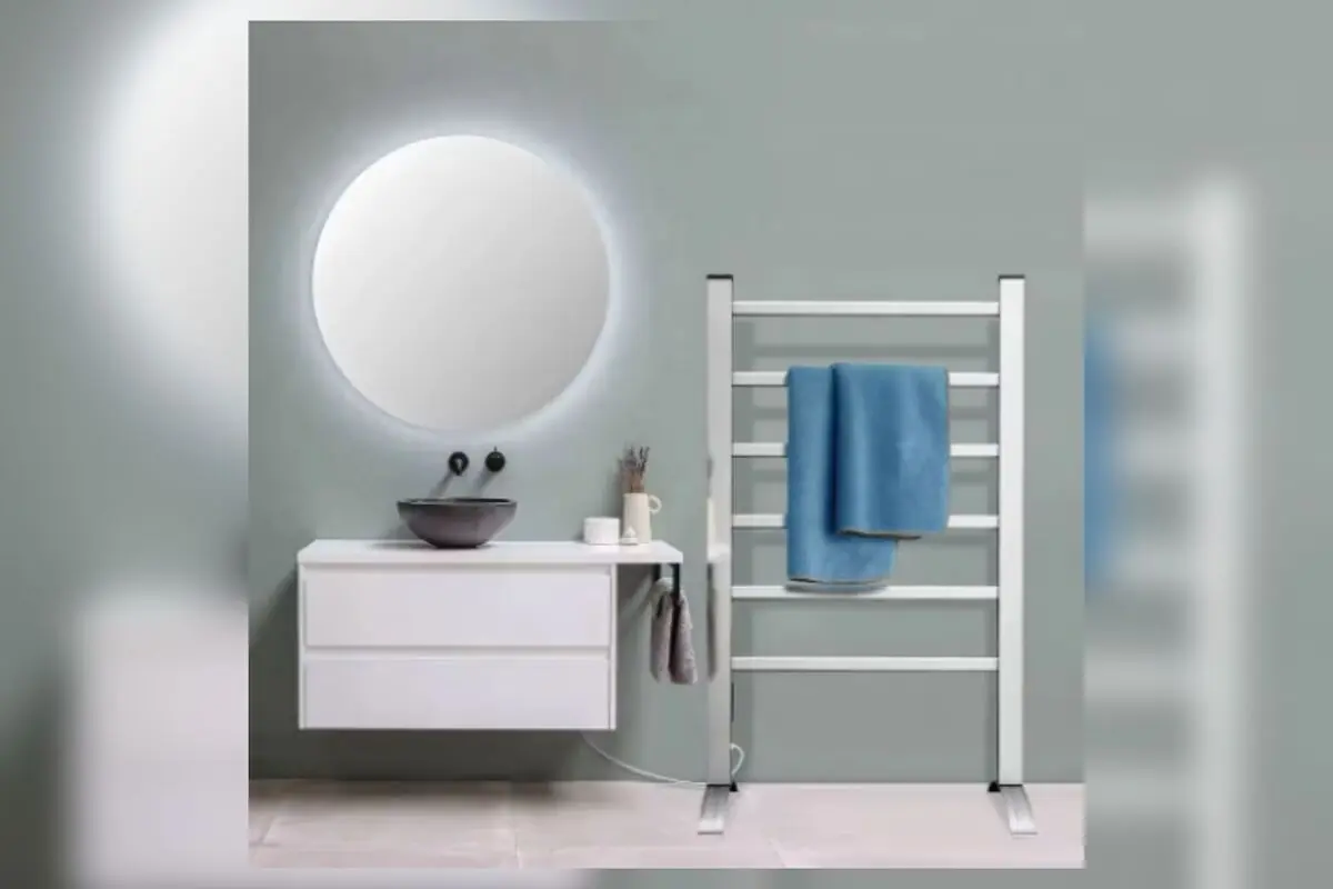 Baño moderno con espejo redondo iluminado mueble blanco flotante y toallero eléctrico con toalla azul Baño moderno con espejo redondo iluminado mueble blanco flotante y toallero eléctrico con toalla azul