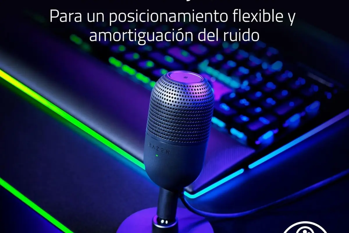 Micrófono Razer de escritorio iluminado en un setup gamer con teclado RGB y texto promocional sobre posicionamiento flexible y amortiguación del ruido