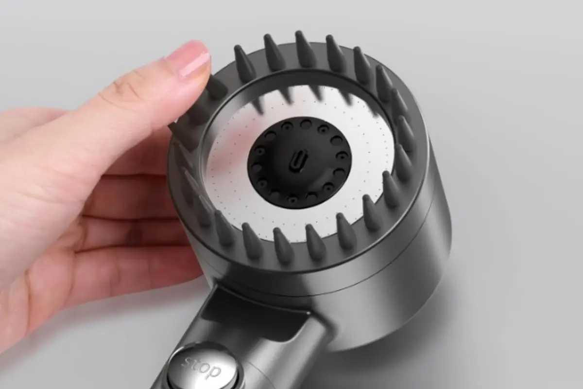 Mano sosteniendo una alcachofa de ducha con cepillo masajeador