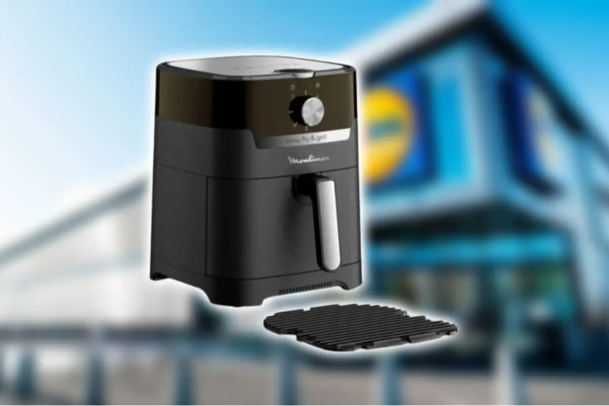 Black air fryer with a rack accessory in front of the blurred facade of a supermarket