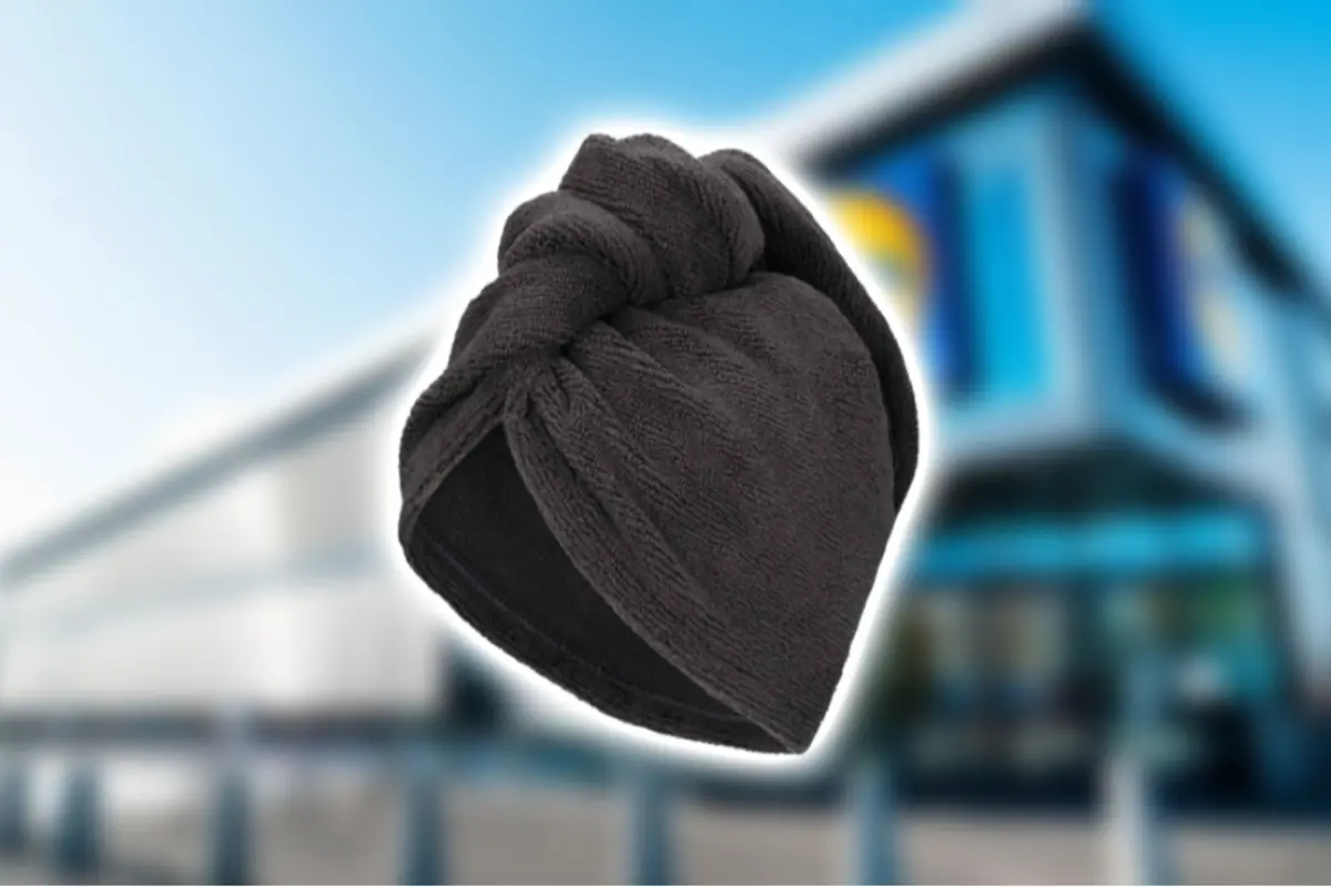 Turbante de toalla negra para secar el cabello sobre fondo desenfocado de edificio moderno