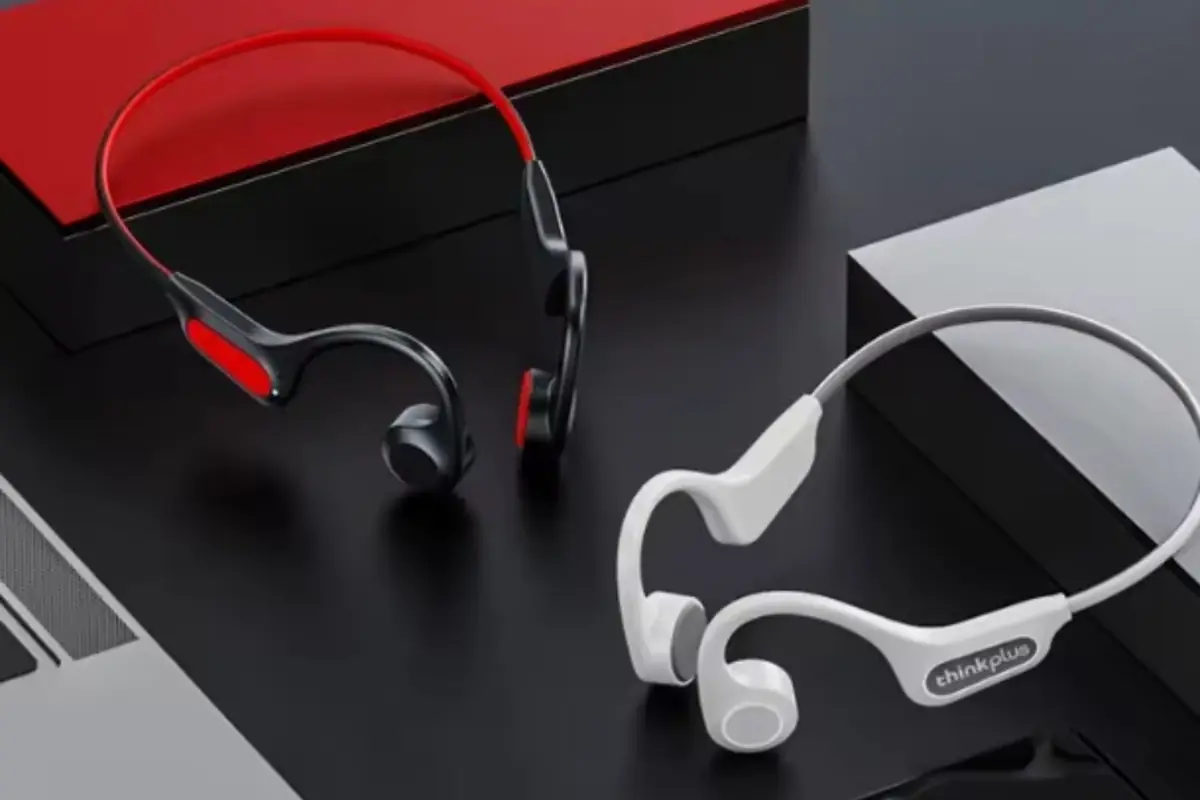 Auriculares de conducción ósea en colores negro con rojo y blanco sobre una superficie oscura junto a cajas rectangulares