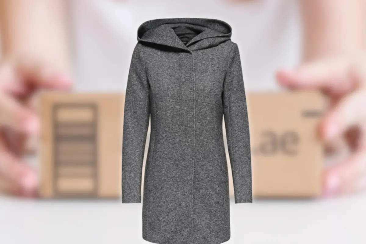 Abrigo gris con capucha en primer plano frente a un fondo desenfocado con un paquete de envío sostenido por unas manos