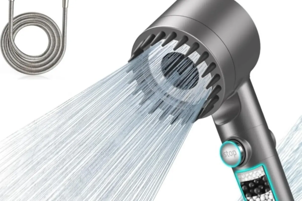 Alcachofa de ducha de mano gris con chorro de agua a presión botón de parada y filtro de esferas minerales junto a una manguera metálica enrollada