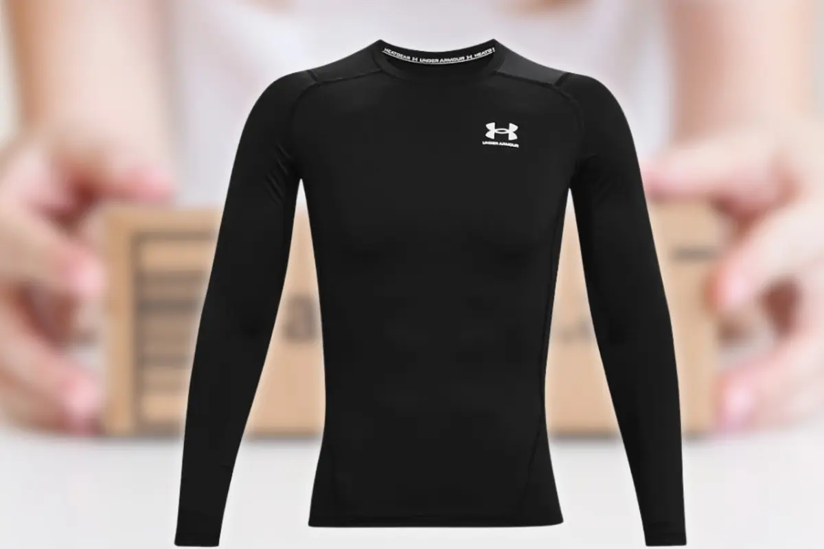 Camiseta deportiva ajustada de manga larga color negro con logo de Under Armour en el pecho sobre fondo desenfocado