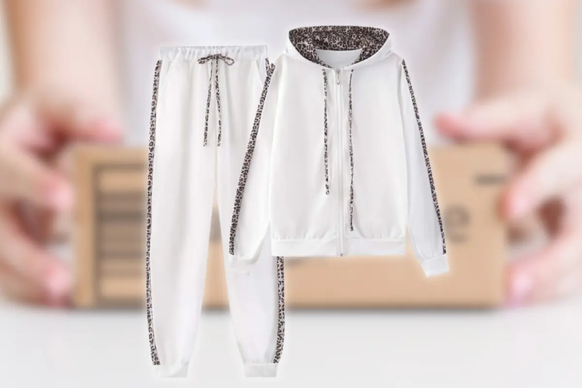 Conjunto deportivo blanco de sudadera con capucha y pantalón con detalles de estampado animal en los bordes sobre fondo desenfocado de paquete de envío