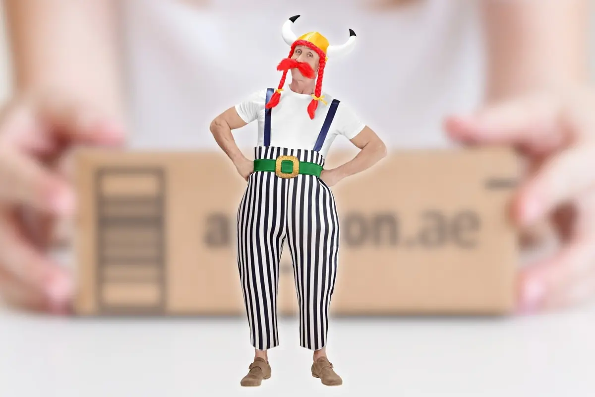 Montaje con hombre disfrazado de Obélix, con casco de cuernos bigote y trenzas rojas pantalones a rayas y tirantes de pie, frente a una caja de cartón desenfocada