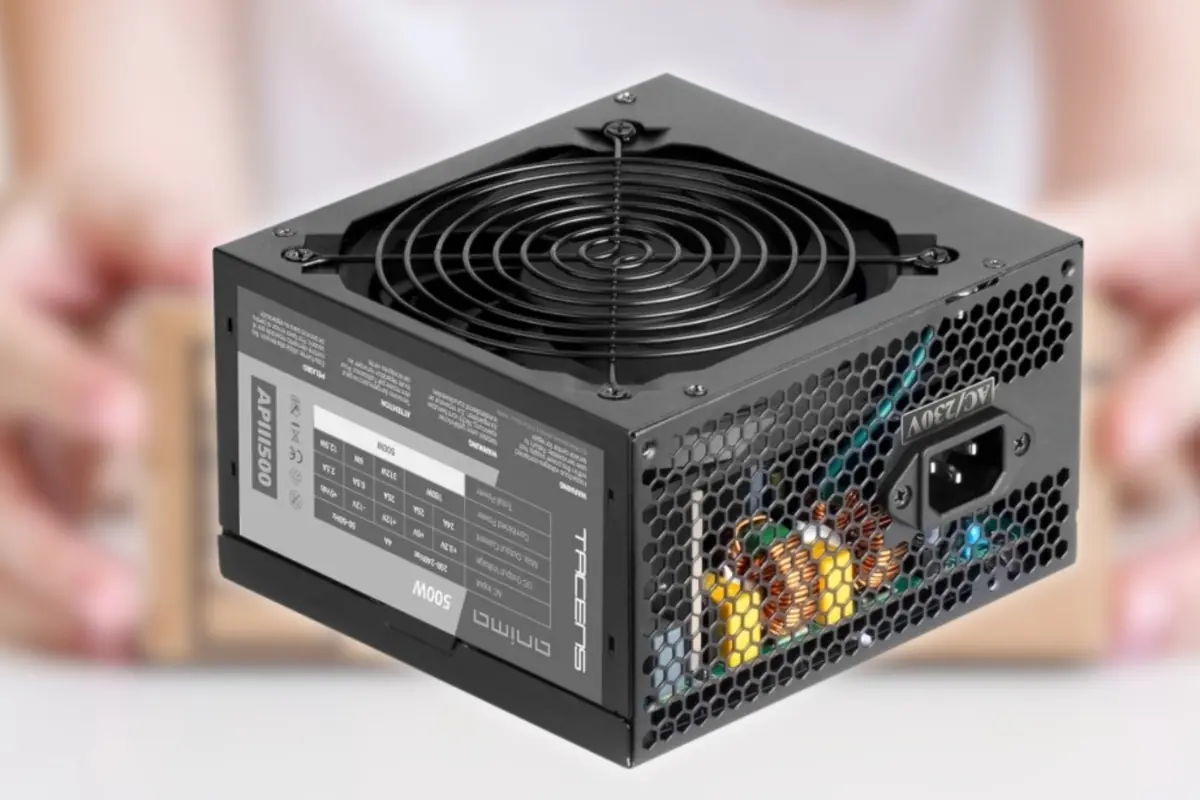 Fuente de alimentación ATX de 500W en color negro con rejilla de ventilación superior y panel lateral con especificaciones técnicas ante fondo desenfocado