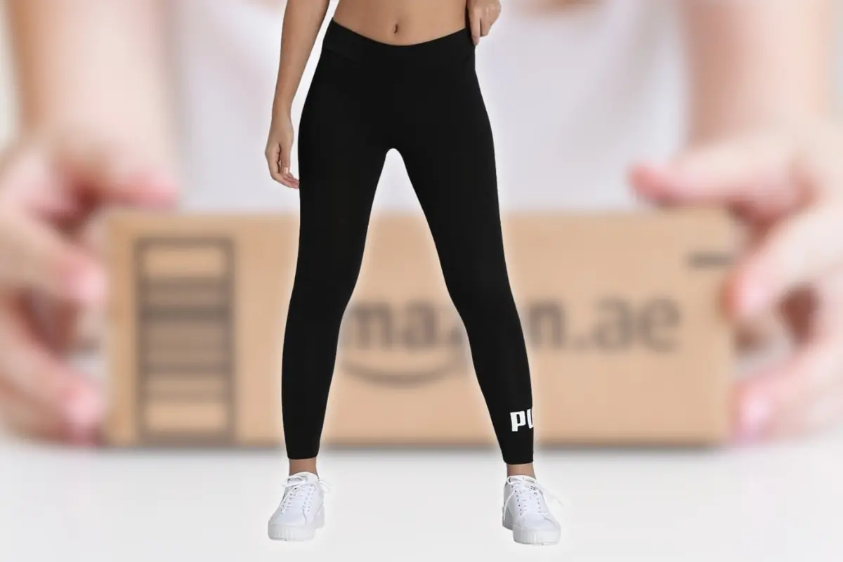 Mujer con leggings negros ajustados y zapatillas blancas posando frente a una caja de envío de Amazon desenfocada