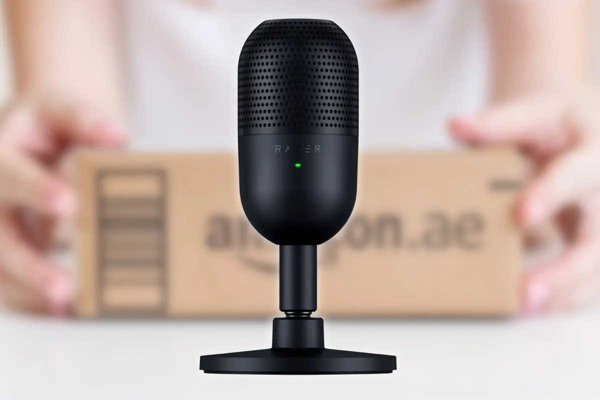 Micrófono negro de escritorio Razer enfocado en primer plano con un paquete de Amazon desenfocado al fondo