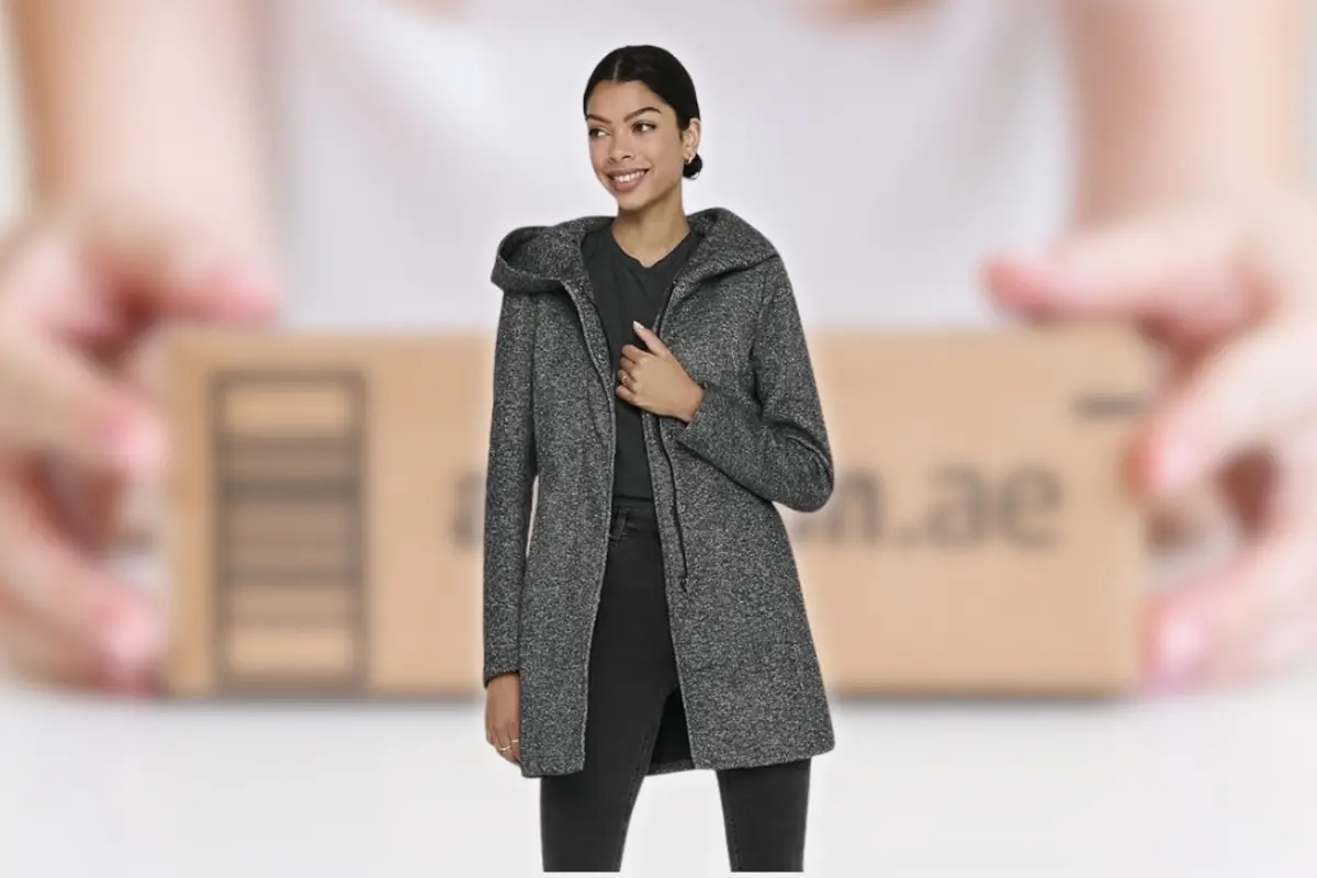 Mujer con un abrigo gris frente a un fondo desenfocado de unas manos sosteniendo una caja