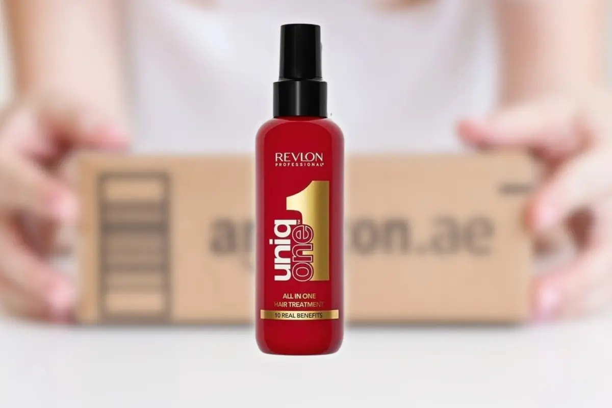 Botella roja de tratamiento capilar Revlon Uniq One en primer plano con un paquete de Amazon desenfocado de fondo