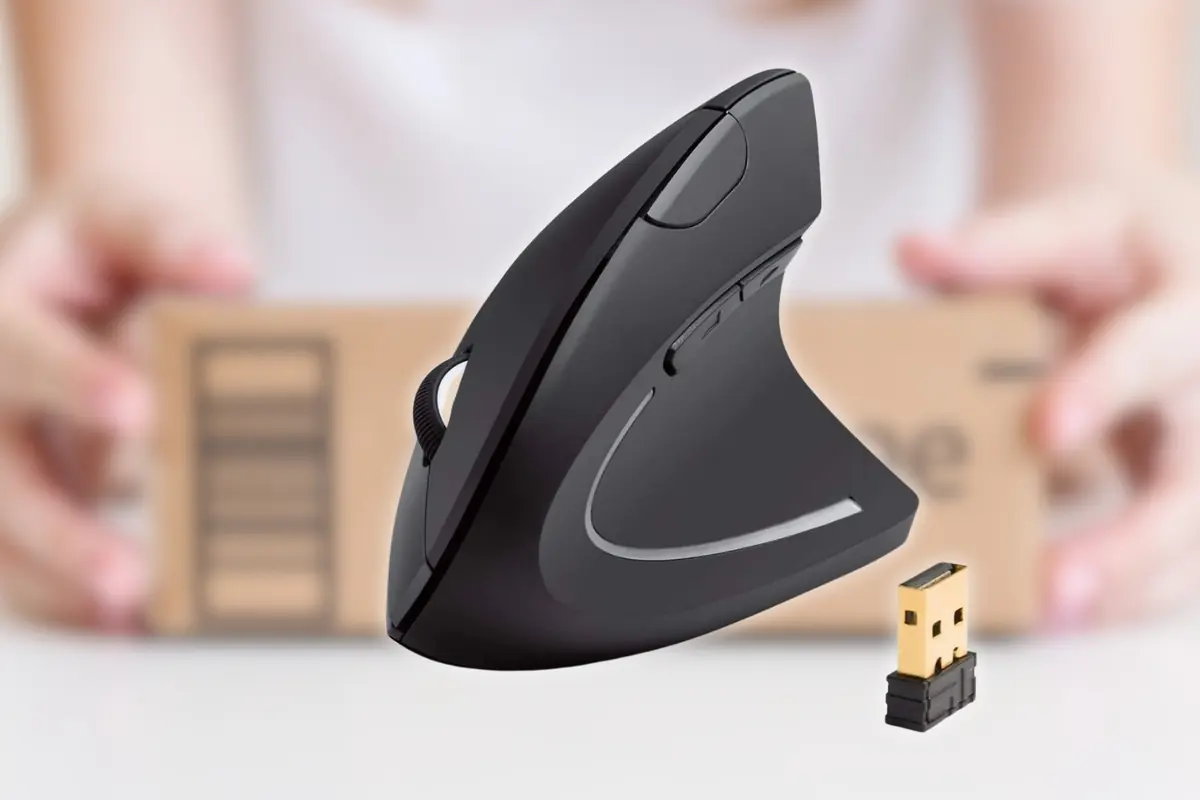 Ratón ergonómico inalámbrico negro en posición vertical con receptor USB dorado delante y una caja de cartón desenfocada al fondo