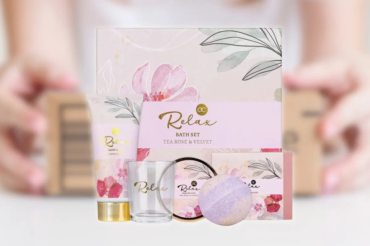 Set de baño relajante con crema de manos vela bomba efervescente y productos aromáticos con diseño floral en tonos pastel, con un fondo de una caja desenfocada
