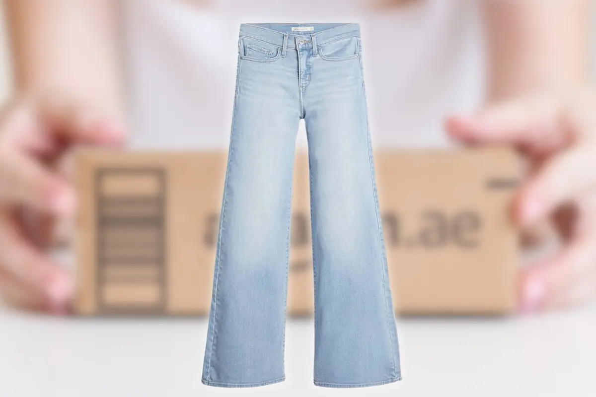 Pantalón vaquero azul claro de pierna ancha sobre un fondo desenfocado con una caja de envío en manos de una persona