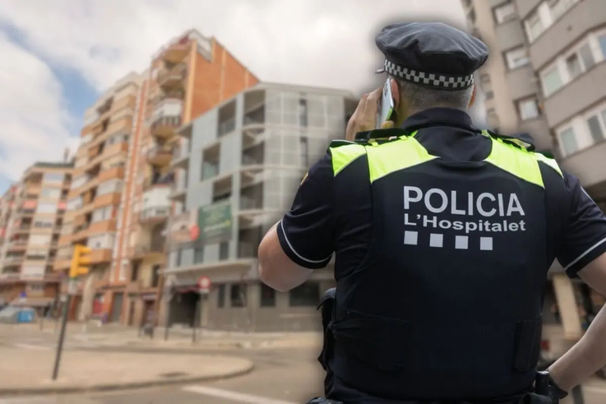 Agente de la policía local de L’Hospitalet de espaldas hablando por teléfono en una calle urbana con edificios de viviendas al fondo