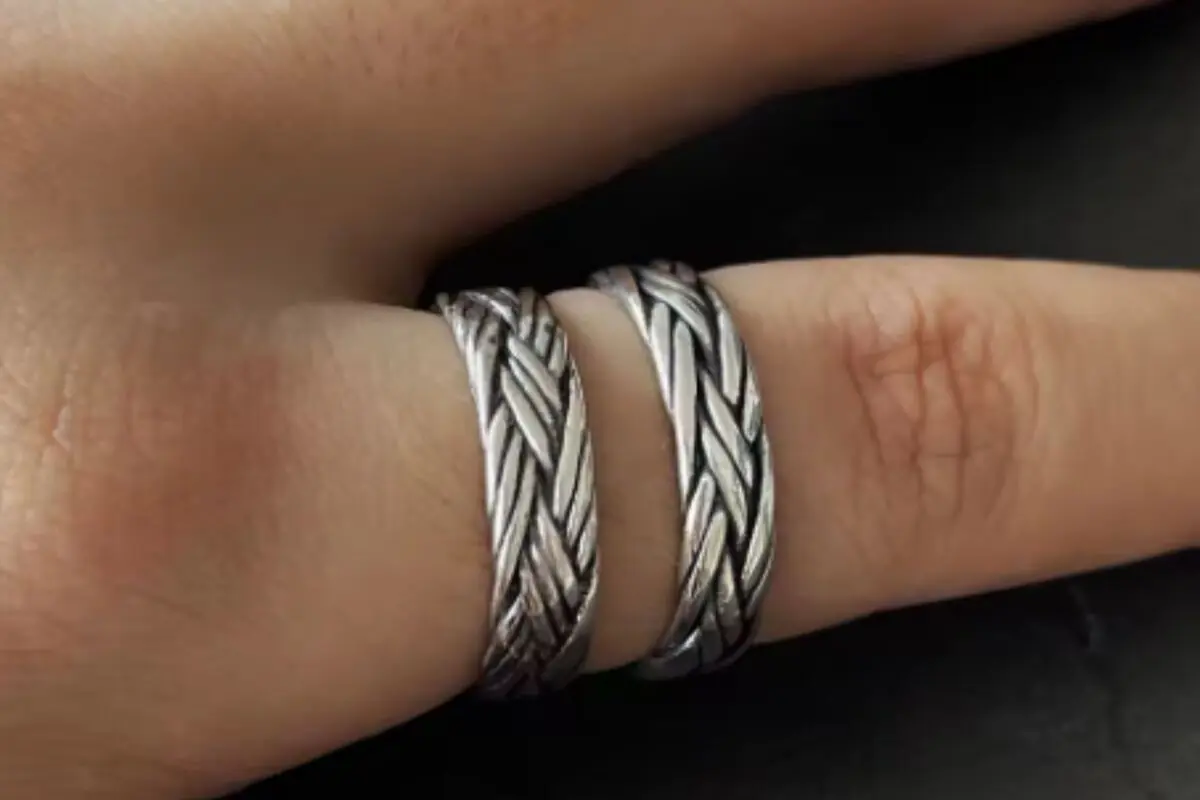 Dos anillos plateados con diseño trenzado colocados juntos en un dedo de la mano