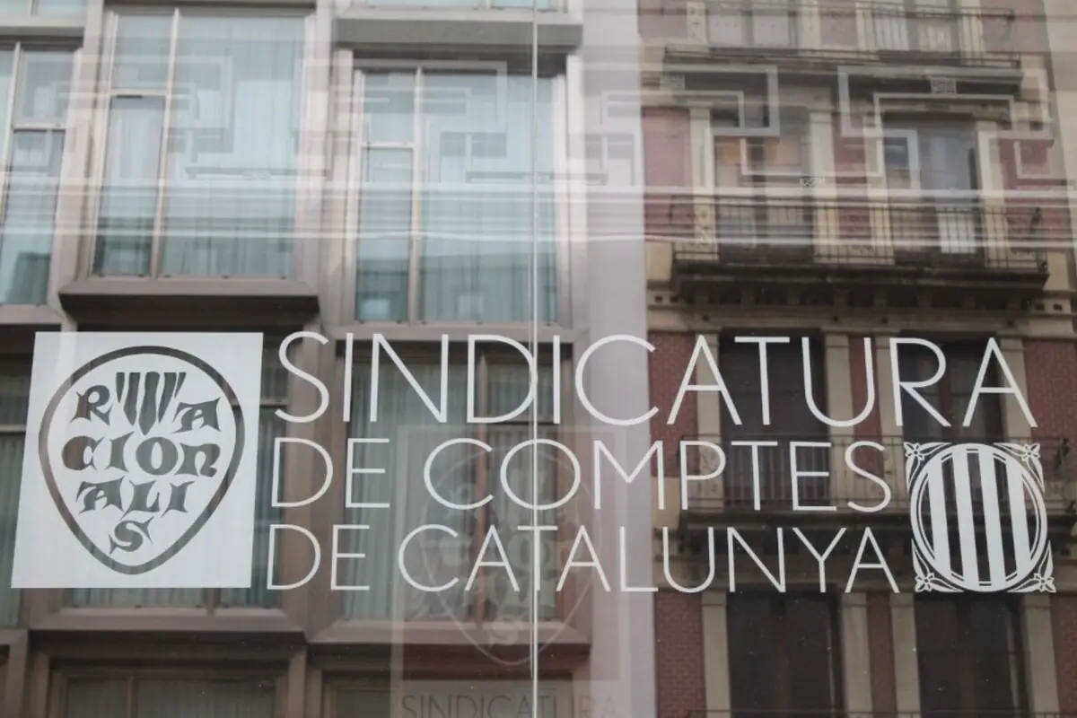 Façana envidrada amb el rètol Sindicatura de Comptes de Catalunya i reflex de edificis urbans