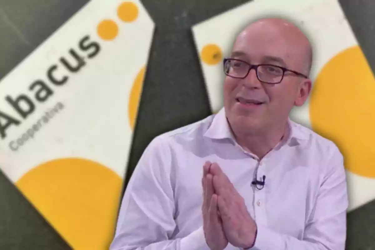 Un hombre con camisa blanca y gafas está frente a un fondo que muestra el logo de Abacus Cooperativa.