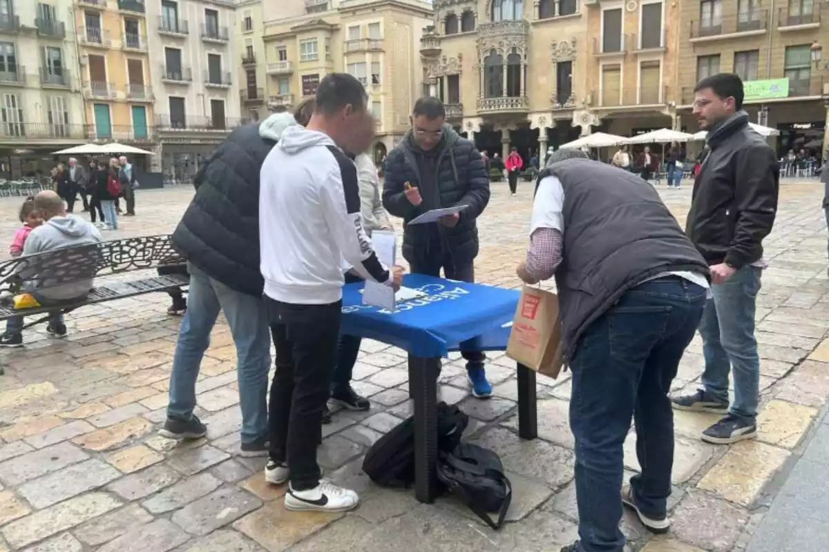 Diverses persones al voltant d'una taula d'Aliança Catalana signant avals per al partit de Sílvia Orriols