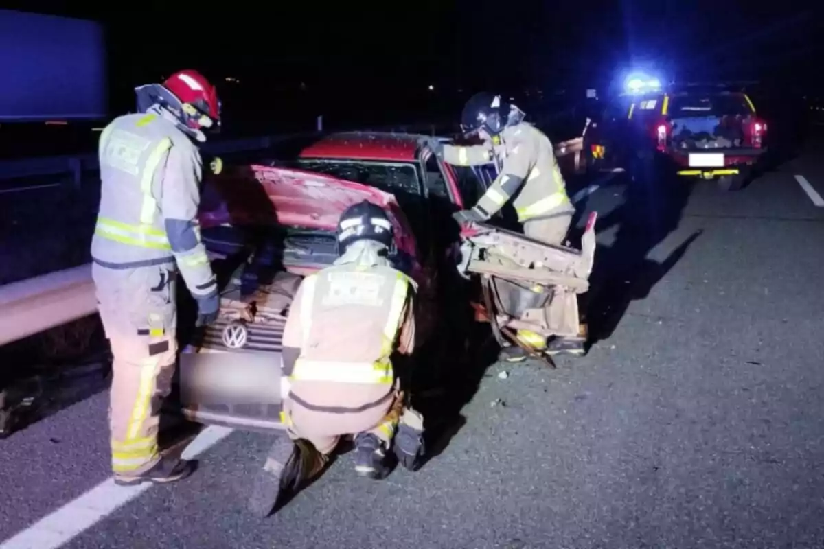 Bombers treballant en un accident de trànsit nocturn a una carretera.