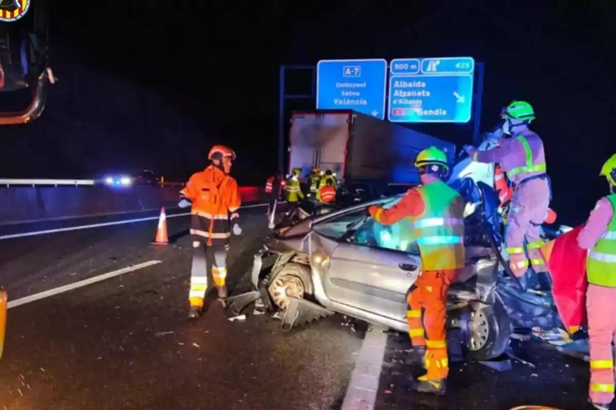 Accident de trànsit nocturn en una autopista amb personal d'emergència treballant al lloc.