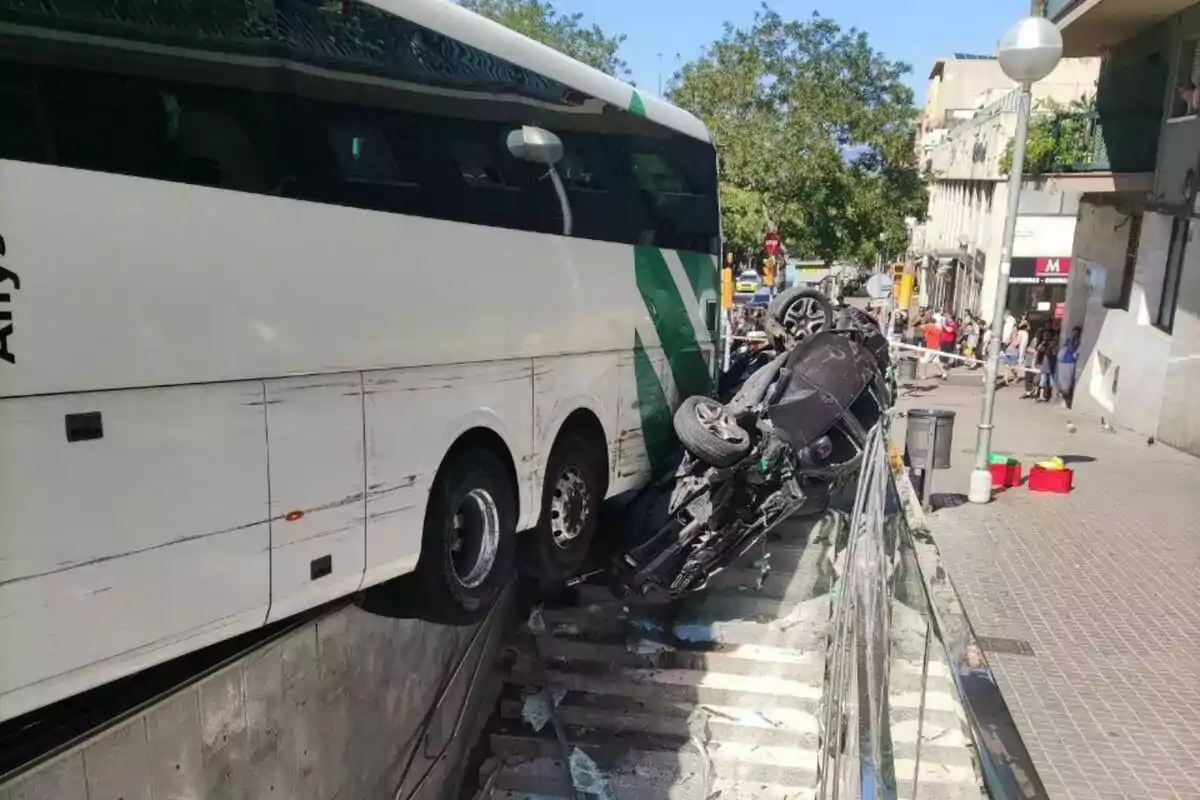 Un autobús i un cotxe accidentat a unes escales en una zona urbana.