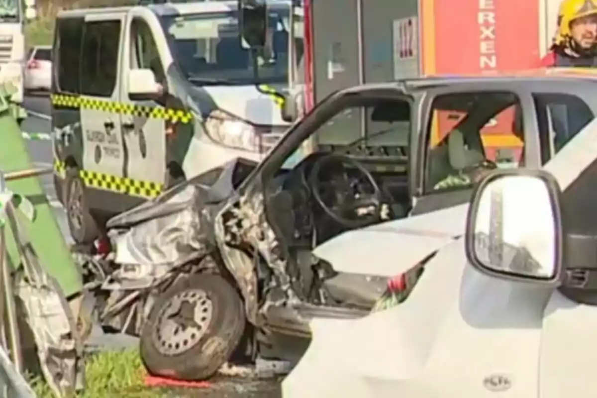 Un vehicle amb danys significatius a la part davantera després d'un accident de trànsit amb un cotxe de la Guàrdia Civil al fons.