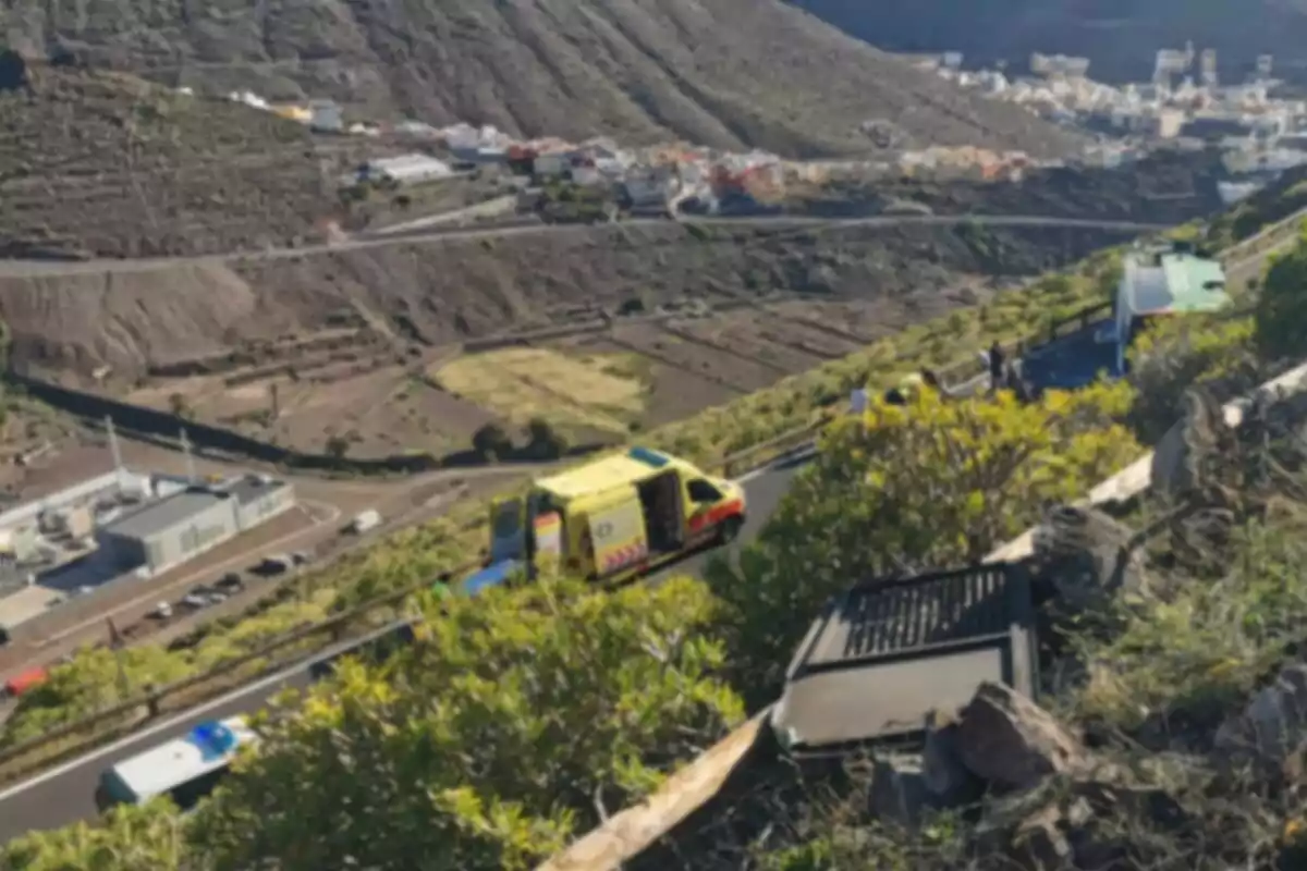 Una carretera de muntanya amb una ambulància groga i diversos vehicles a la via, envoltada de vegetació i un paisatge muntanyós al fons. Una carretera de muntanya amb una ambulància groga i diversos vehicles a la via, envoltada de vegetació i un paisatge muntanyós al fons.