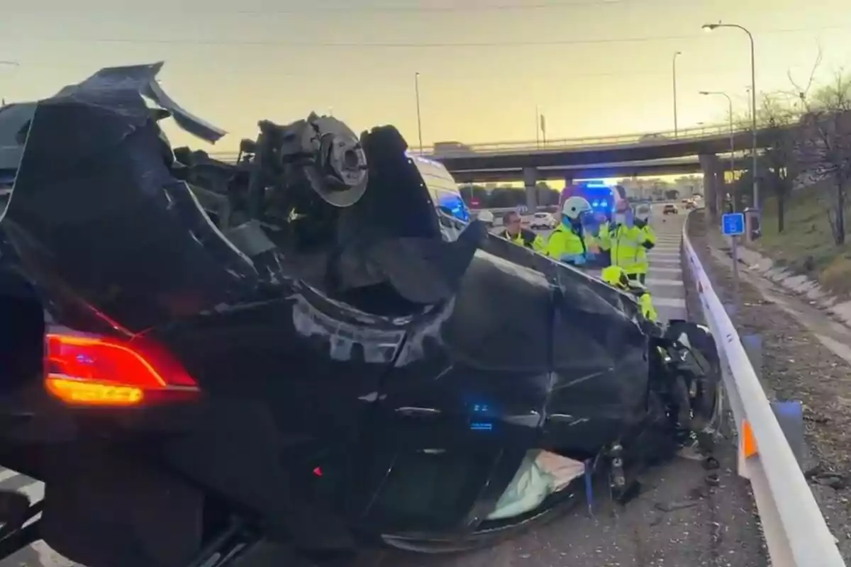 Un cotxe bolcat en una carretera amb diversos agents d?emergència al voltant i llums de vehicles d?emergència encesos.