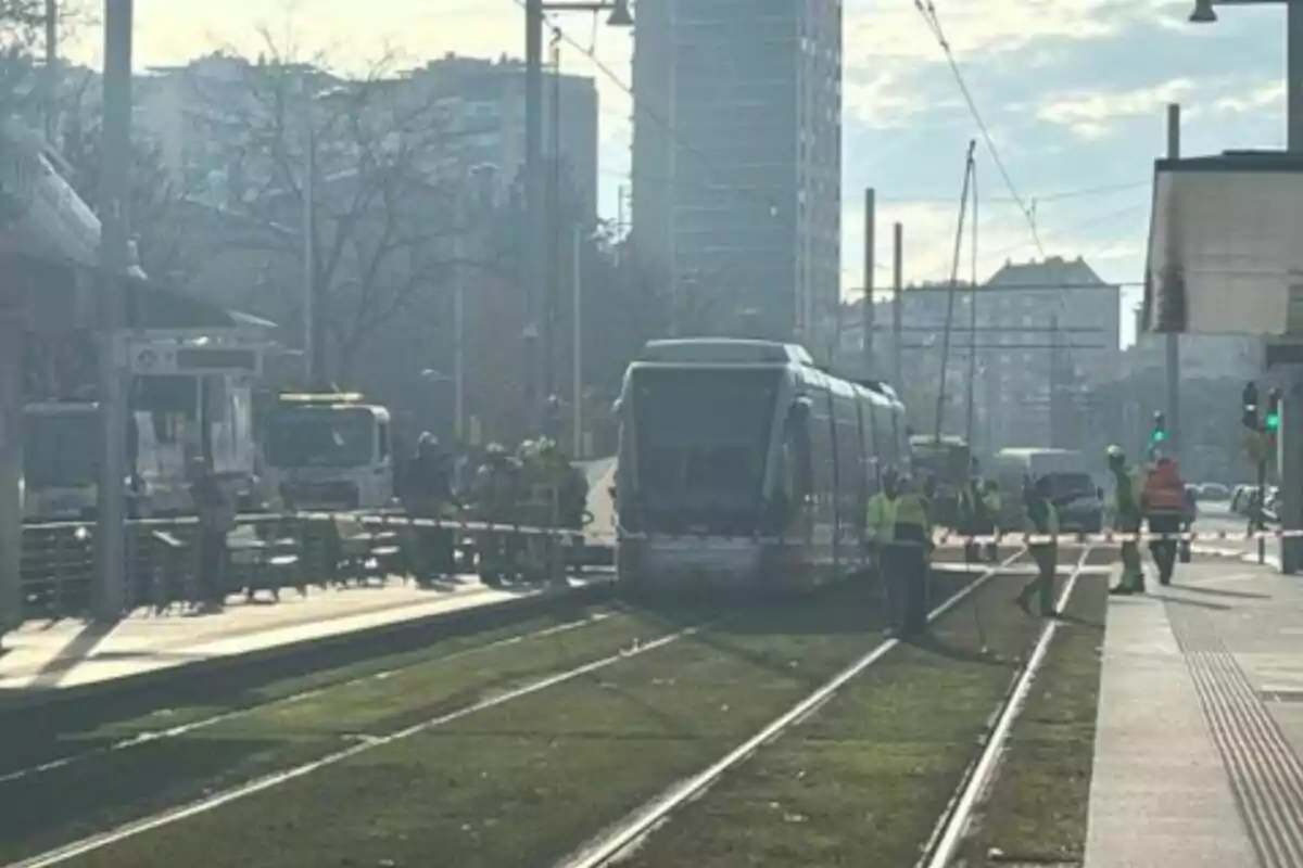 Un tramvia detingut en una via amb treballadors al voltant d'una ciutat.