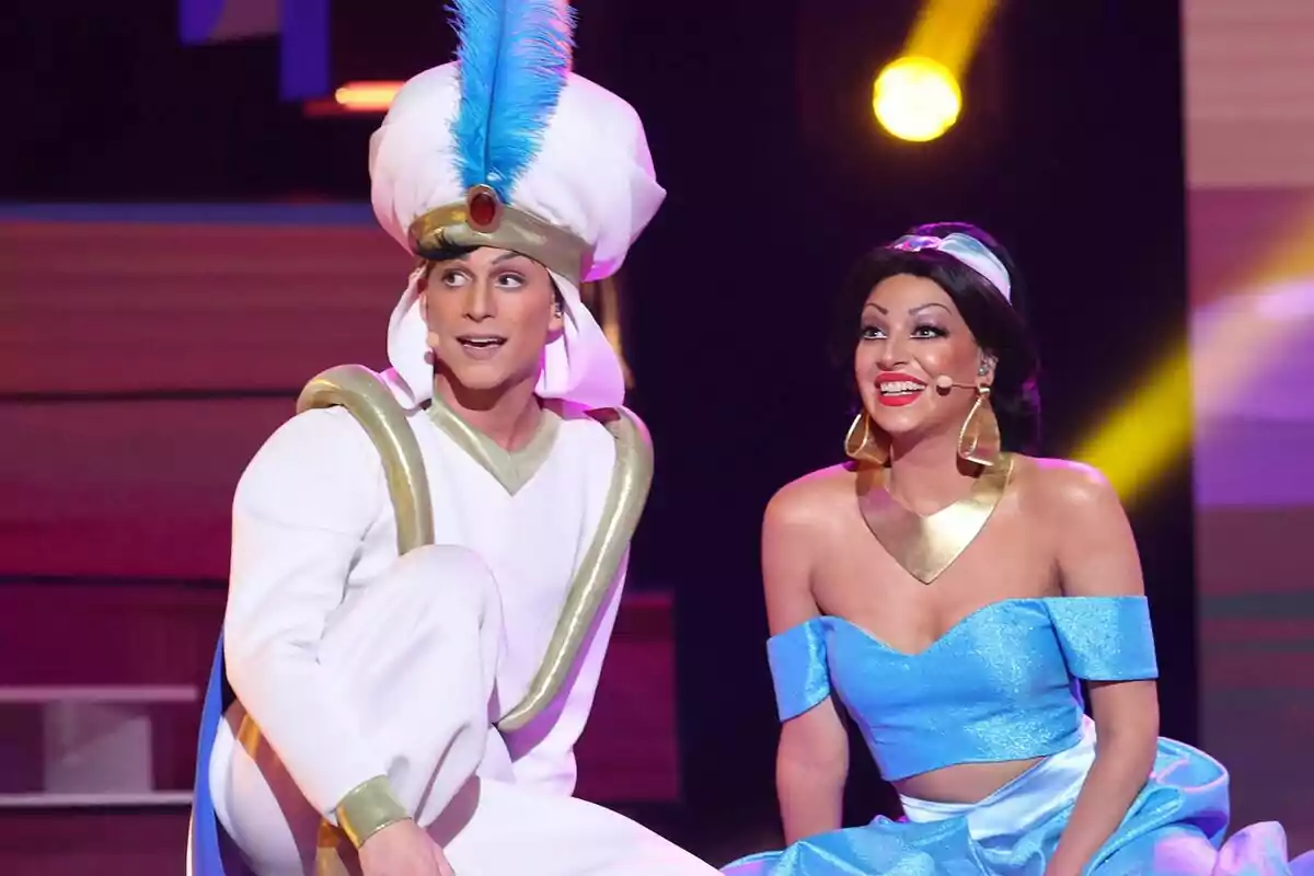 Raoul Vázquez i Ana Guerra disfressats d’Aladí i Jasmine somriuen en un escenari il·luminat de Tu Cara Me Suena Raoul Vázquez i Ana Guerra disfressats d’Aladí i Jasmine somriuen en un escenari il·luminat de Tu Cara Me Suena
