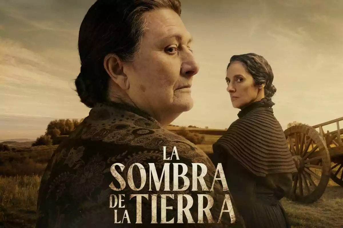 Baladre Calvo i María Morales vestides d'època miren en direccions oposades en un paisatge rural amb un carro de fusta al fons i el text "L'Ombra de la Terra" al centre.