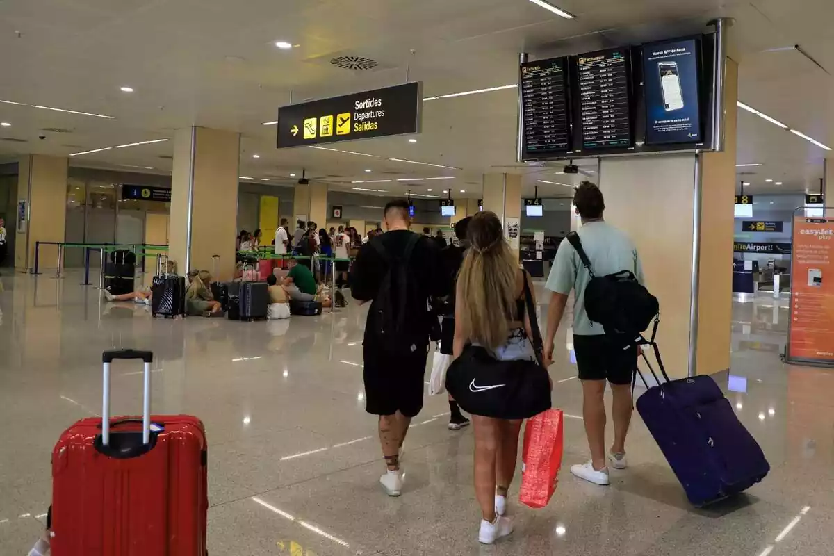 10 d'agost del 2023, Espanya, Eivissa: La gent mira la pantalla de la terminal de l'aeroport d'Eivissa