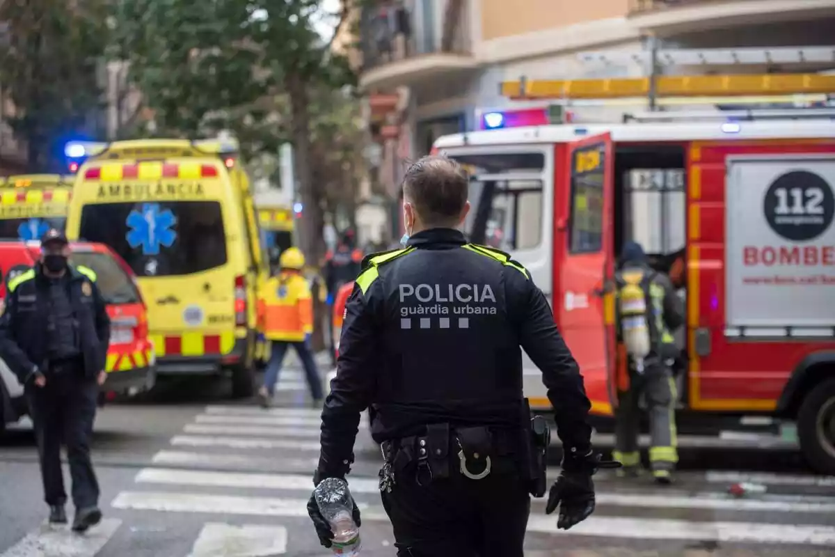 Fotomuntatge d?un agent de la Guàrdia Urbana, amb diverses ambulàncies i una dotació dels Bombers de la Generalitat