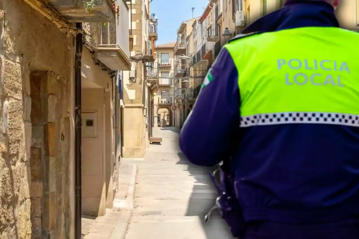 A local police officer with his back turned observes a narrow and empty street in an urban setting.