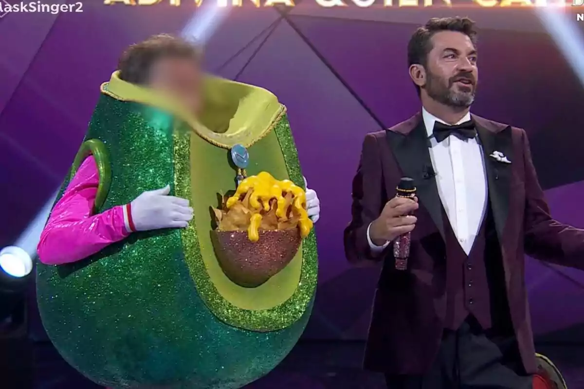 Una persona disfressada d'alvocat amb nachos i formatge amb la cara pixelada amb Arturo Valls a Mask Singer