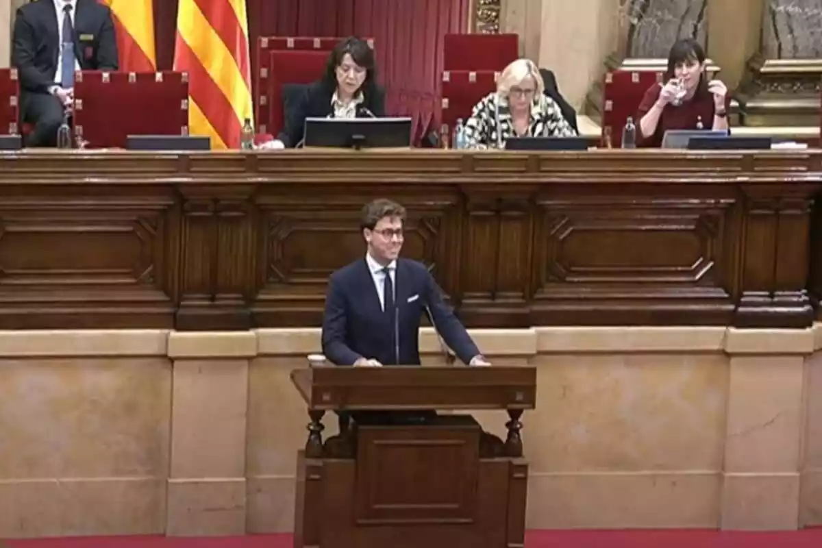 Alberto Tarradas al faristol del Parlament de Catalunya ia la part superior els membres de la Mesa del Parlament Anna Erra i Aurora Madaula