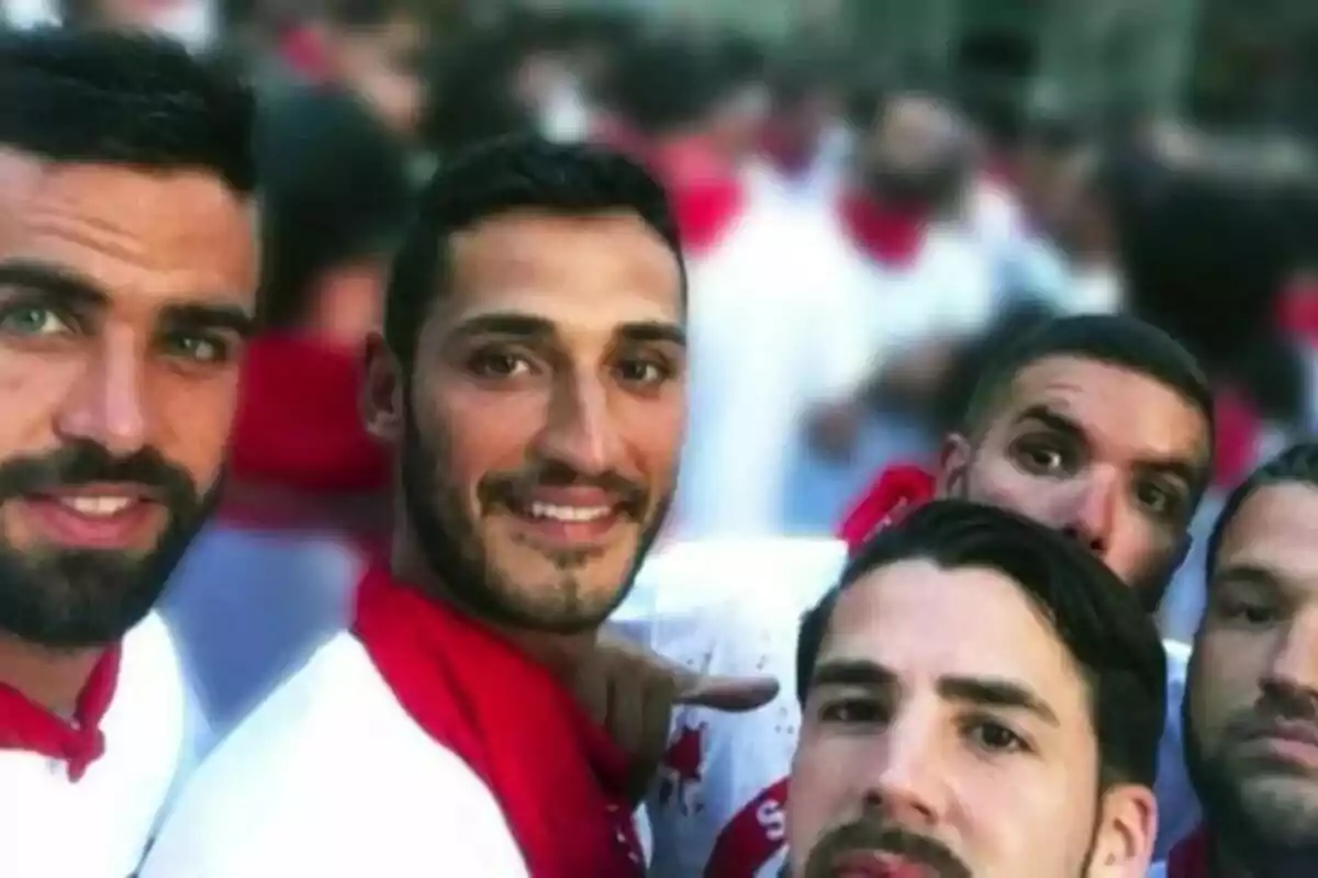 Cinc homes joves posen per a una selfie vestint samarretes blanques i mocadors vermells en un ambient festiu. Cinc homes joves posen per a una selfie vestint samarretes blanques i mocadors vermells en un ambient festiu.