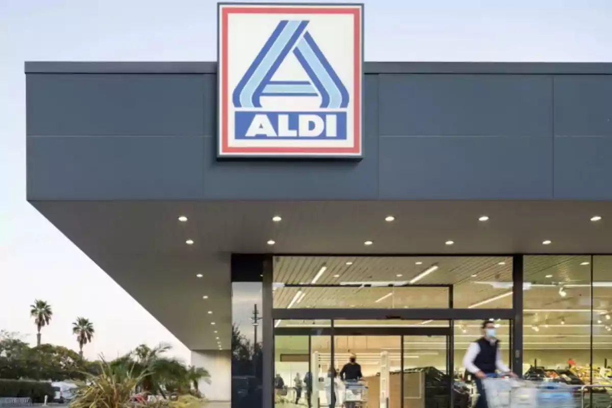 Façana d'una botiga amb el logotip d'ALDI a la part superior i persones sortint amb carretons de la compra.