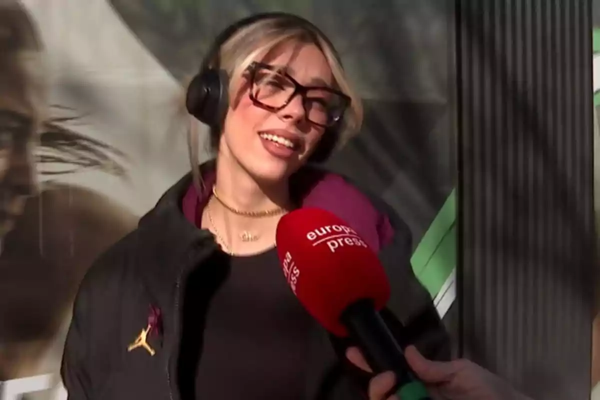 Alejandra Rubio with headphones and glasses is being interviewed by a Europa Press microphone.