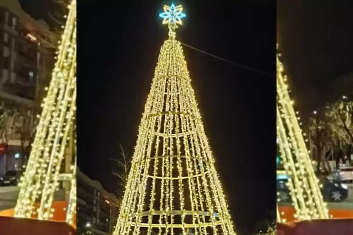 Arbre de Nadal il·luminat amb llums daurats en un carrer a la nit.