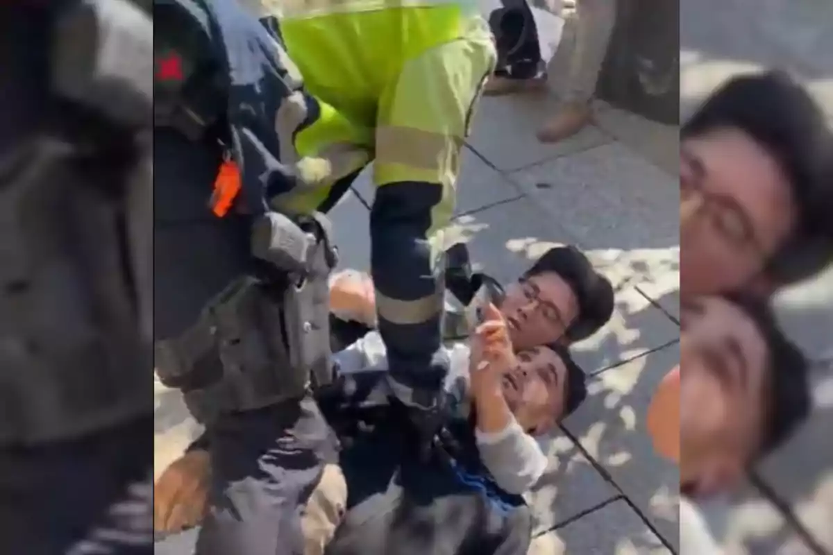 Un oficial de policia deté dues persones a terra durant un incident al carrer.