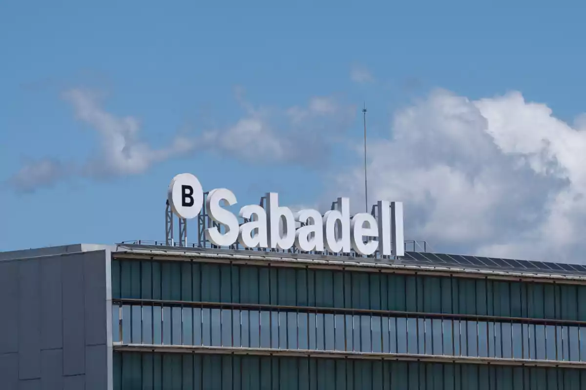 Building with the Sabadell logo on top under a blue sky with some clouds.